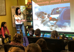 Dzieci oglądają ilustrację przedstawiającą samochód produkujący spaliny
